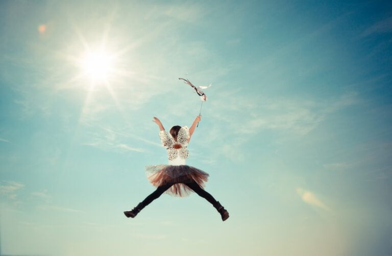 A young girl wearing costume butterfly wings jumps in the air