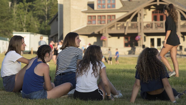 Girls sitting with their two counsellors at summer camp - Muskoka Woods