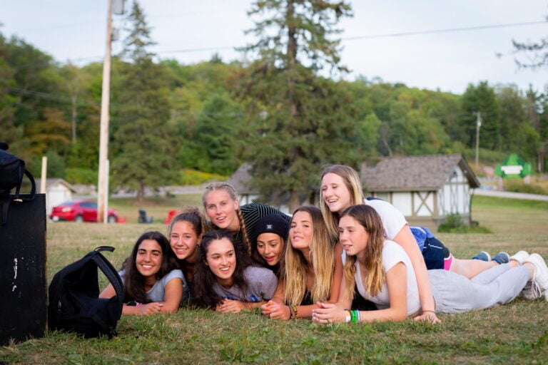 A group of teen girls lie on their stomachs in a field