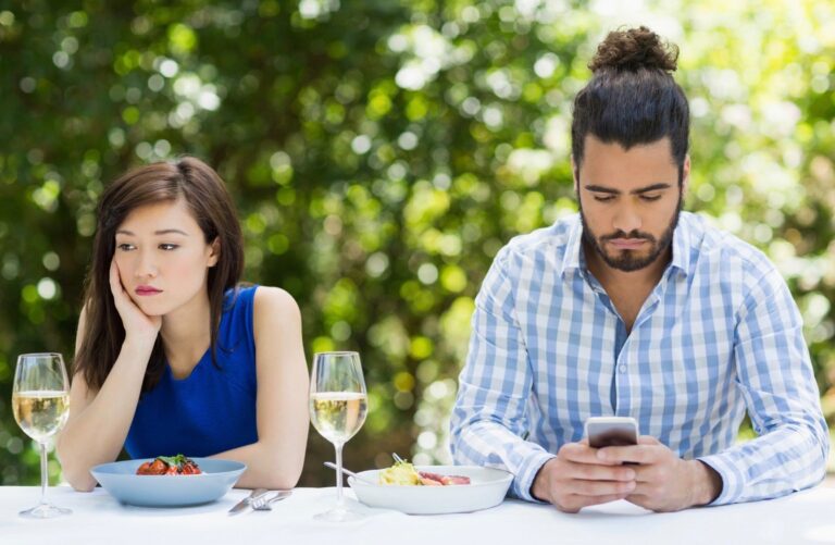 A man ignores his companion while using his cell phone