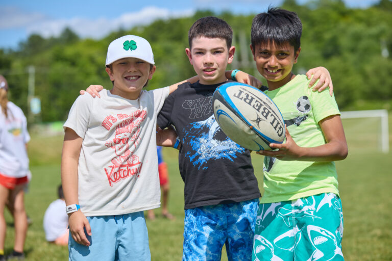 Three Muskoka Woods guests pose for a photo while holding a footbal
