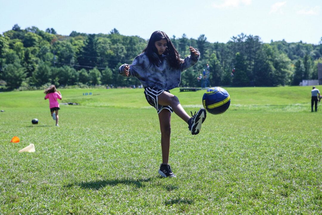 a girl kicks a soccer ball